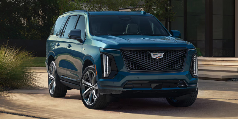 The image shows a sleek, modern 2025 Cadillac Escalade, a luxury SUV with a bold front grille and stylish design.