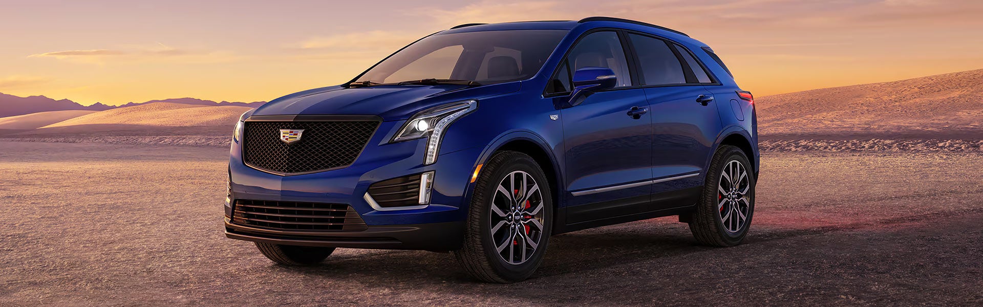 2026 Cadillac XT5 SUV in blue shown from front three-quarter view at sunset.