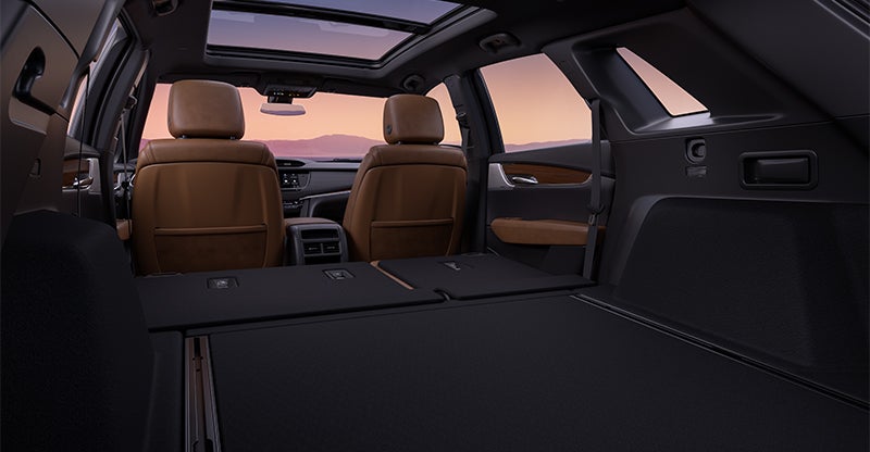 Cadillac SUV cargo area with rear seats folded flat, showing expanded storage space.