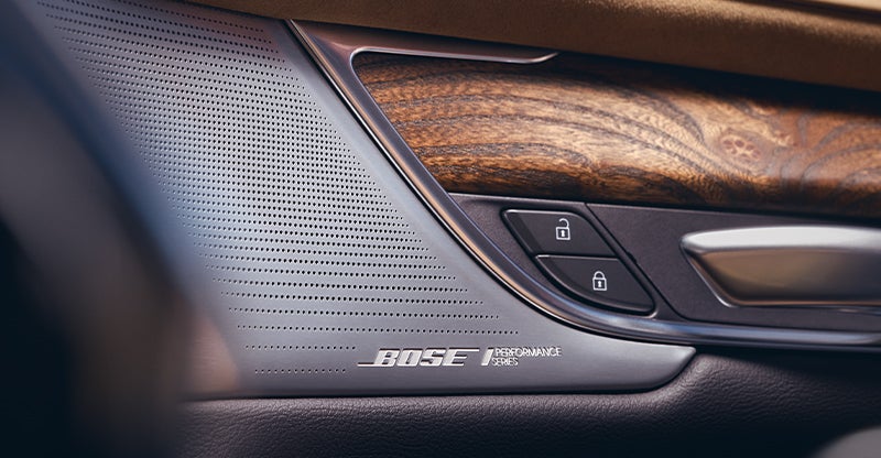 Close-up of Cadillac interior speaker grille with BOSE branding and wood trim detail.