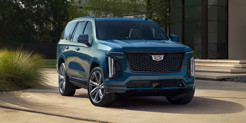 Front view of a 2026 Cadillac Escalade in blue, highlighting its bold grille and premium design.